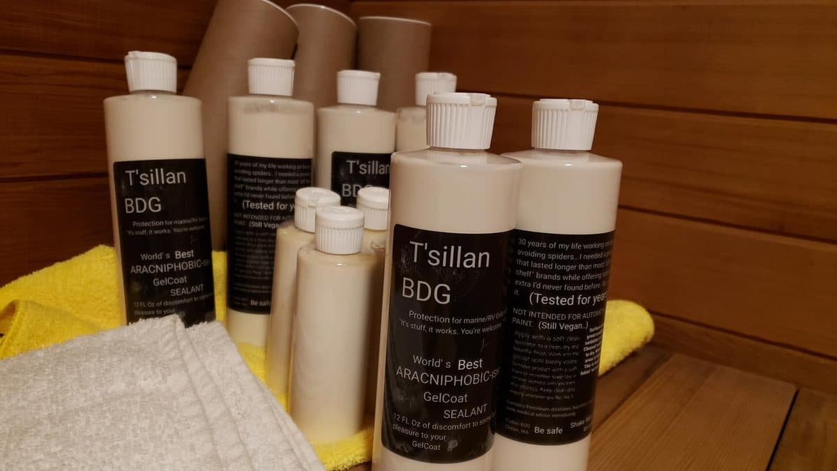 A group of T'sillan BDG bottles on a wooden workshop bench alongside a yellow microfiber towel and a folded gray terrycloth towel.